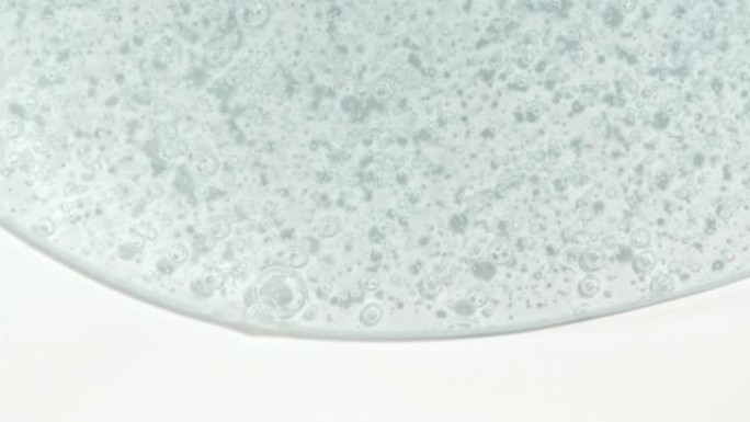 透明蓝色化妆品液体凝胶的宏观拍摄，白色表面有气泡向下流动的乳霜。天然有机化妆品，医药。