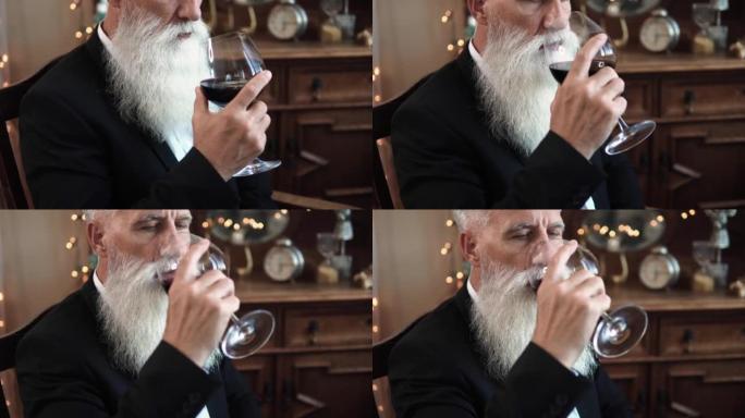 英俊的大胡子老人喝红酒