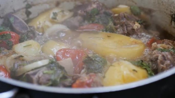 在大锅里煮一道美味的肉菜，配上蔬菜、香料和香草，用慢动作煮。用锅煮亚美尼亚卡什喇嘛的特写。民族美食