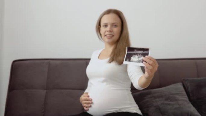 一名皮肤白皙的孕妇抚摸她的肚子，并显示了胎儿超声诊断的照片