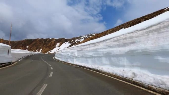 在奥地利阿尔卑斯山的达施泰因的大格洛克纳附近的边缘，驾驶汽车通过高雪块的狭窄曲线的POV
