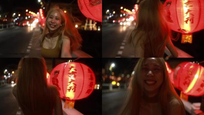 农历新年元宵节，慢动作年轻的亚洲女孩在中国灯笼之间的街道上奔跑。夜间街头旅行。