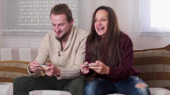一对夫妇坐在沙发上玩电子游戏