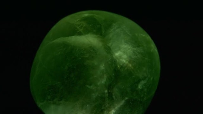 黑色背景上旋转的绿色萤石岩石