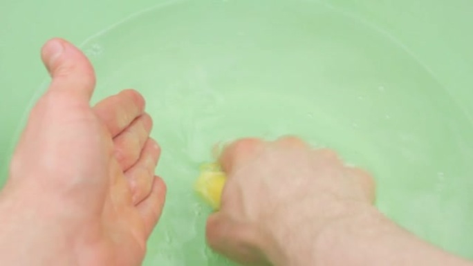 一个人用固体肥皂洗手，close-up.Washing用固体肥皂在盆里洗手。