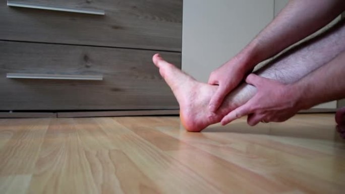 欧洲男子在跟腱断裂手术后通过手动治疗和康复锻炼伸展跟腱，尽管疼痛的疤痕疼痛，以恢复脚跟脚踝和腿部的力