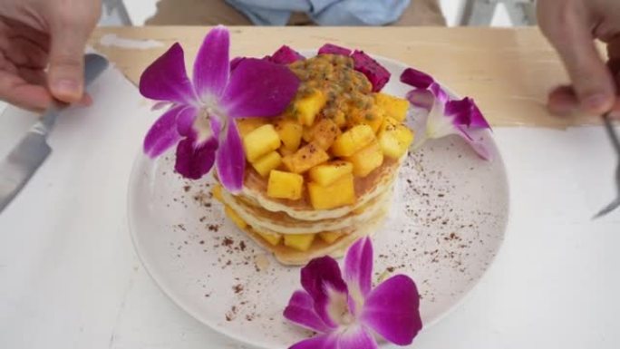 美味的煎饼和热带水果放在盘子里。健康早餐