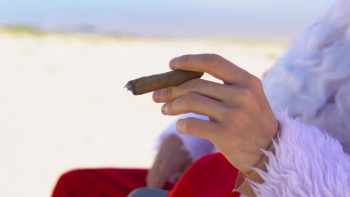 戴着墨镜的圣诞老人躺在沙滩上的日光浴躺椅上抽古巴雪茄。热带地区的圣诞老人