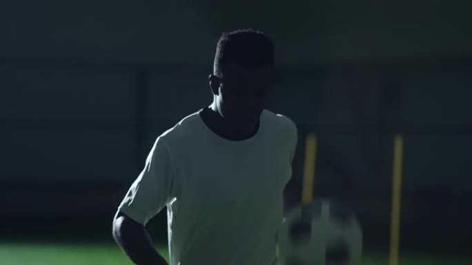 黑人足球运动员在运动中心踢球，中等慢动作肖像，积极消遣