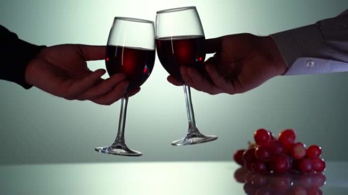 红酒齐打，干杯概念。以慢动作拍摄。两个人戴眼镜。餐桌上的新鲜葡萄