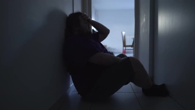 患有精神疾病的人独自坐在家里的走廊上。精神痛苦中的孤独男人