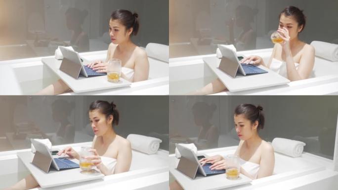 在浴缸里的平板电脑上在线工作的女商人。