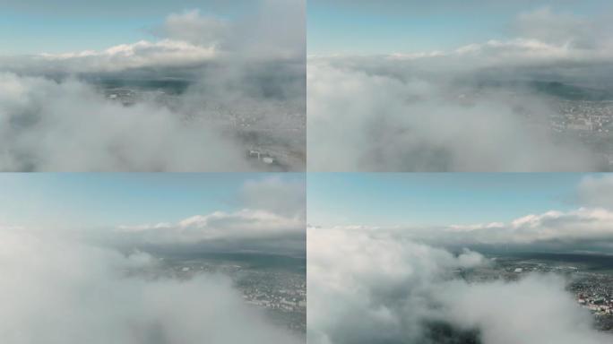 通过低云层鸟瞰山区郊区。在云层之上，白天的飞行在云层之上，可以看到山上的城市