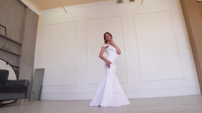 穿着白色连衣裙的理想新娘在站立时为摄影师摆姿势。