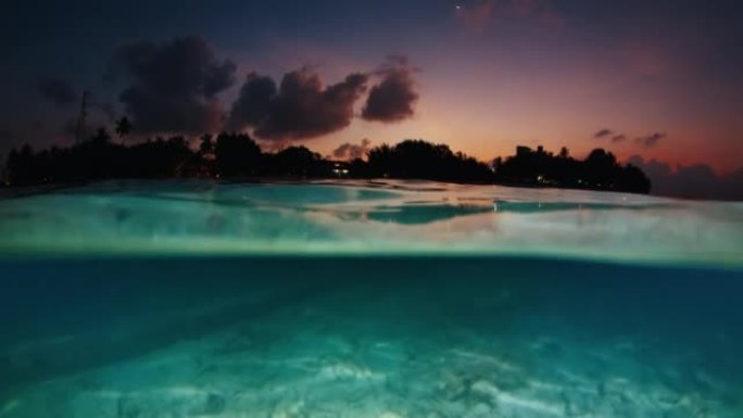 岛屿夜海。暮色晚期热带平静海和岛屿的水下分裂景观