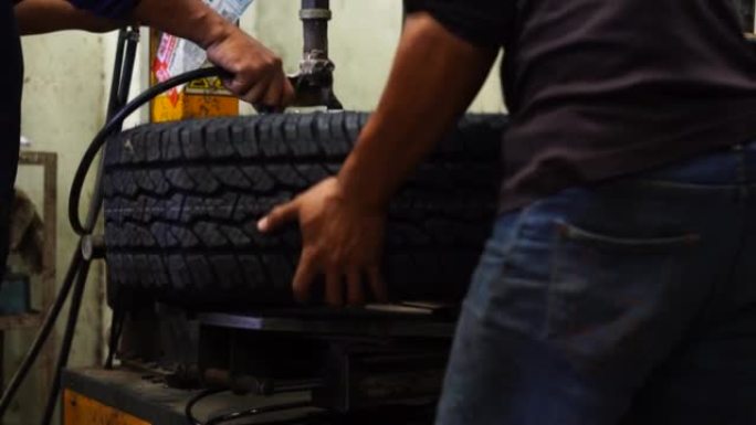 一名熟练的机械师正在修理厂更换车轮平衡器上的轮胎。