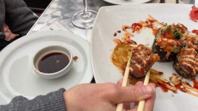 女人用筷子拿寿司卷蘸酱油