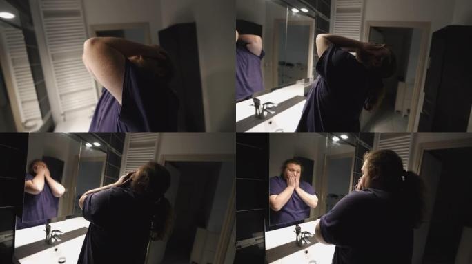 一名绝望的年轻超重男子在浴室镜子前遮住脸，感到生活问题不堪重负