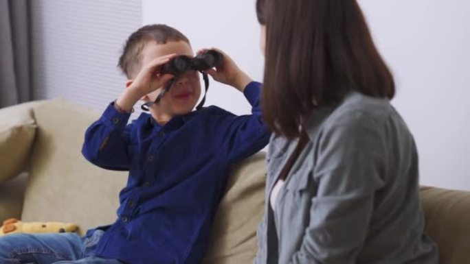 微笑的儿子用双筒望远镜看着妈妈