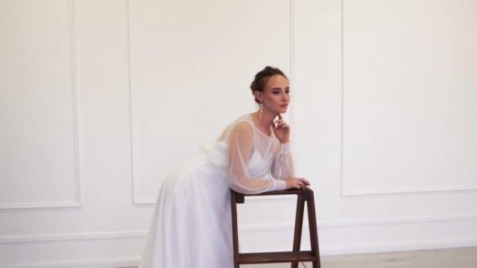 一个穿着白色婚纱的女孩靠在架子上，优雅地摆姿势。