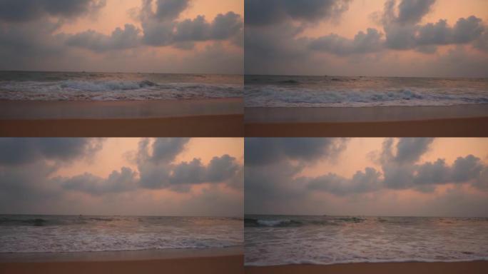 在印度果阿的北果阿，落日期间，卡兰特海滩的广角慢动作拍摄，云彩在海洋上方。日落后，海面上的云波与戏剧