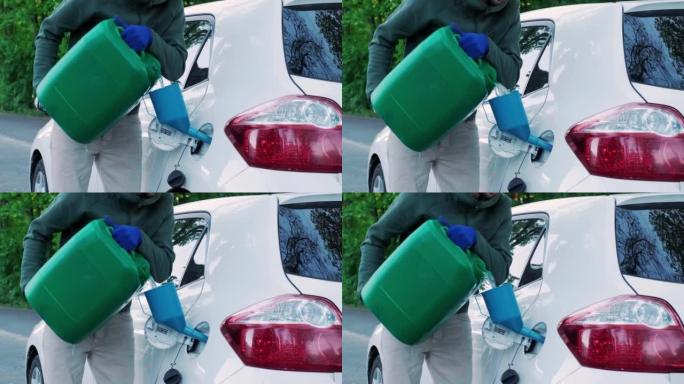 一名男子从塑料红色汽油罐将汽油倒入空油箱。将汽车从罐中注入油箱的颈部。