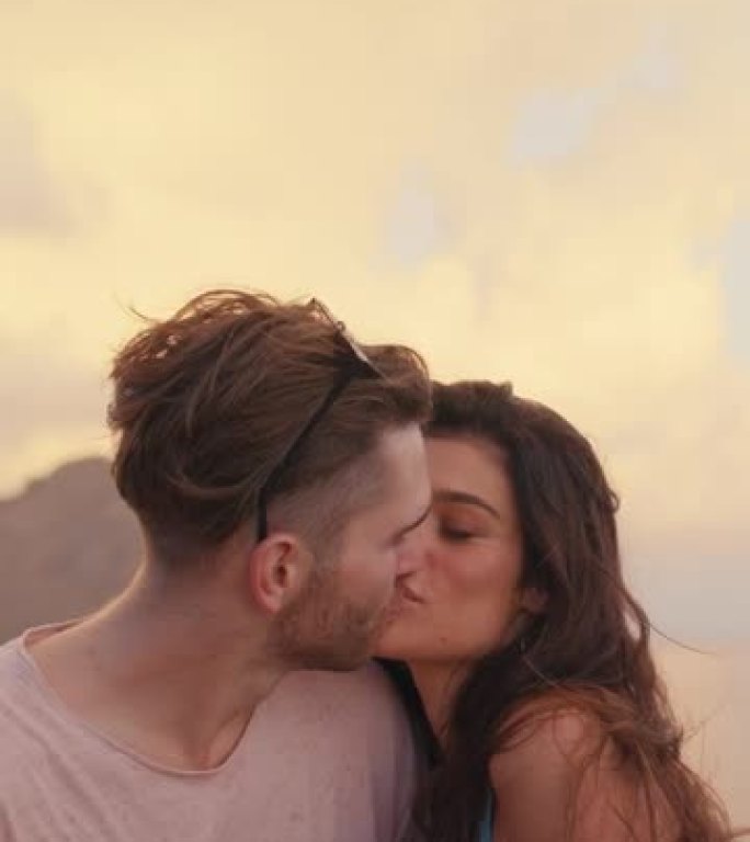 浪漫的夏天。夫妇在度假时观看日落的美景，亲吻脸颊垂直视频