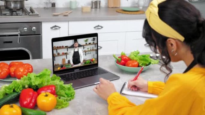 厨房里的女人打招呼在线学习视频通话笔记本电脑听厨师写