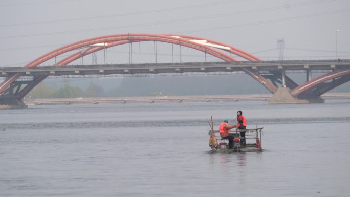 潮白河中工人驾驶着水草收割机作业