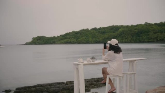 女人在热门而著名的旅游胜地用手机拍摄美丽的景色。