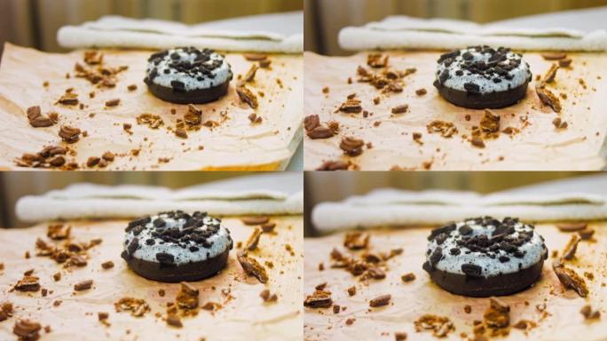 用奥利奥饼干装饰的巧克力甜甜圈。甜甜圈在用天然巧克力装饰的纸上。微距和滑块拍摄。面包店和食品概念。各
