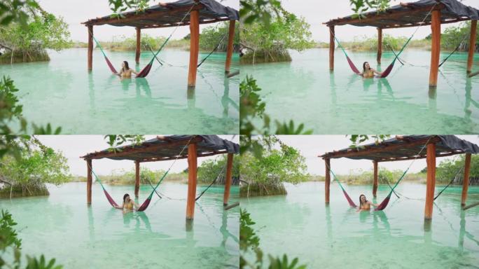 在墨西哥Bacalar泻湖的水中的吊床中休息的女人