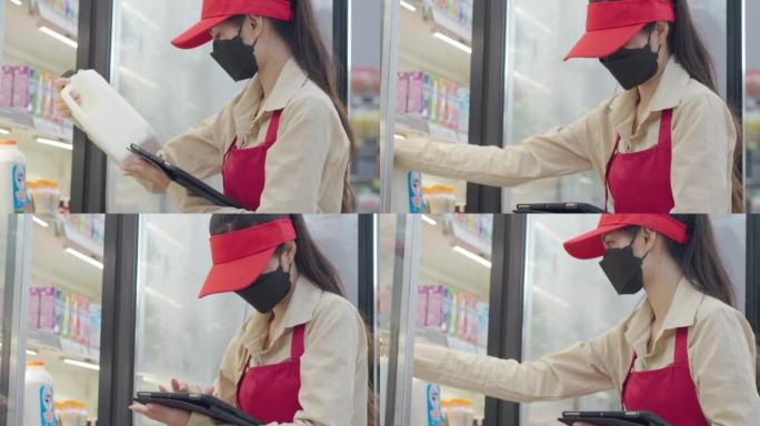 亚裔女超市员工用平板电脑检查冷柜新鲜食品