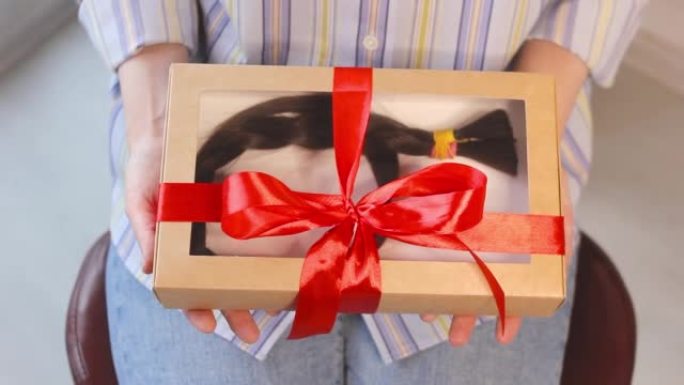 女人拿着长辫子的礼品盒，捐赠发型，天然头发