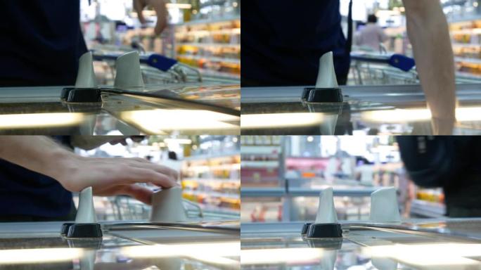 购物中心冷藏室推拉门的特写镜头，一名男子滑动并拿走冷冻食品包装