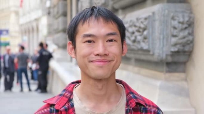 街头学生博客游客中年轻英俊的亚洲男子红衫对镜头微笑的肖像