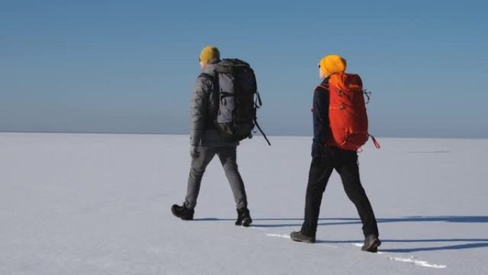 背着背包的男人和女人走过雪场。慢动作