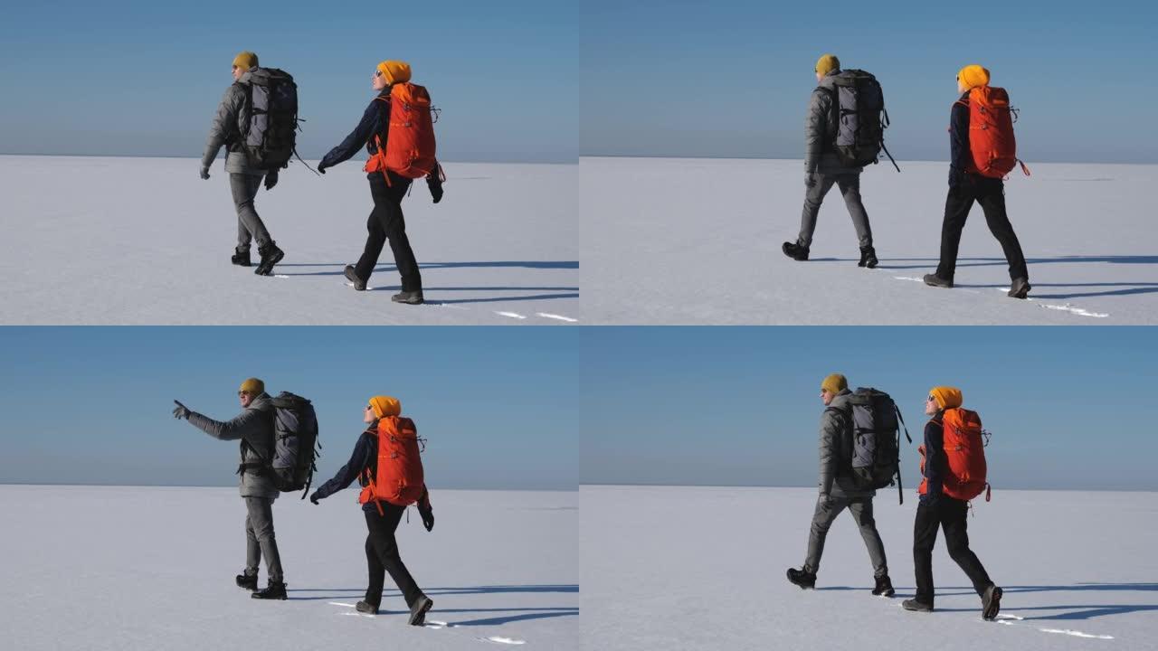 背着背包的男人和女人走过雪场。慢动作