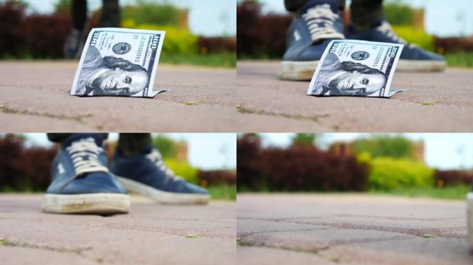 人行道上一百美元钞票的特写镜头，一个走路的人找到了它