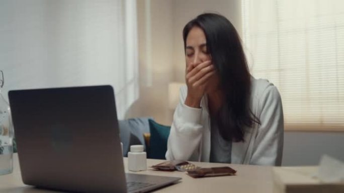 生病的年轻亚洲妇女使用笔记本电脑在家里的客厅与医生交谈。