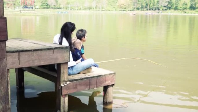亚洲母亲和他的儿子早上在湖中钓鱼
