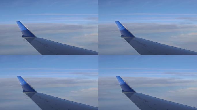 有趣的是，通过窗户看到飞机机翼在多云的天空上方飞行，背景是蓬松的云层