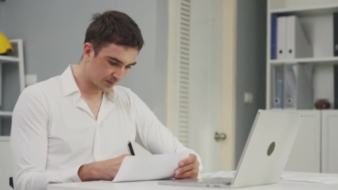 坐在现代办公室里的年轻商人使用笔记本电脑