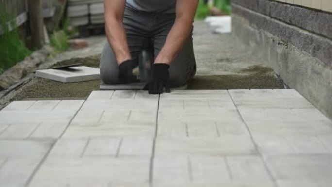 男子用橡胶槌和水平在地板上铺设铺路砖