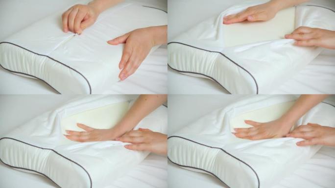 一名妇女解开枕套的纽扣，将手压在矫形枕头的泡沫记忆上