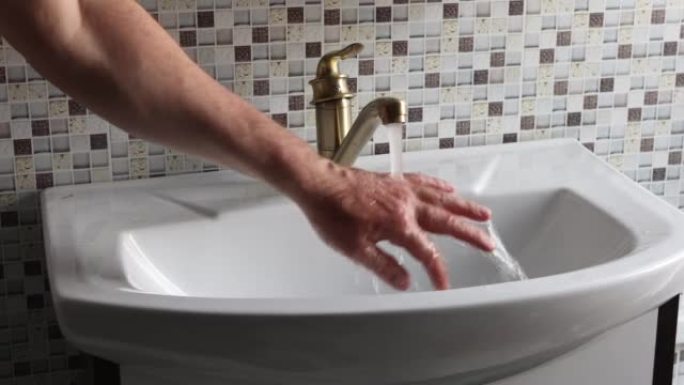 浴室里的黄铜单肘杠杆单声道混音器水龙头，手正在检查水温。