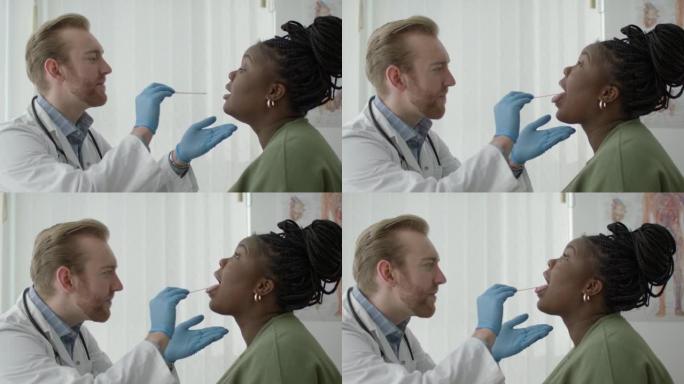 参加医生预约的年轻黑人妇女。年轻的医生在检查病人时使用压舌板。