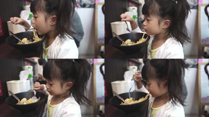 三岁的小女孩在日本餐厅吃拉面，她好饿。亚洲孩子在外面吃饭。