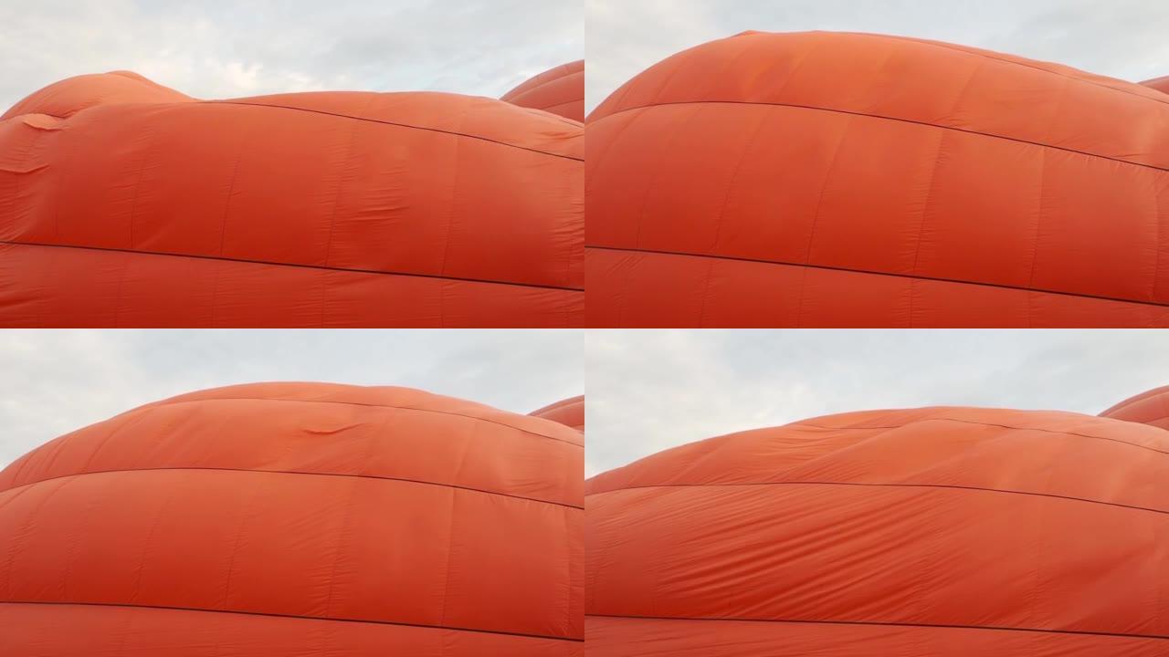 当在蓝天的背景下膨胀时，一个大的橙色气球的球体会美丽而平稳地摆动。