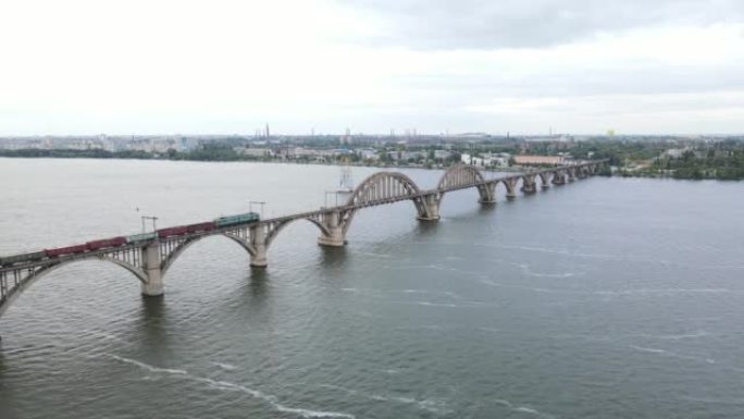 一列火车穿过一座美丽的桥的鸟瞰图。货运列车在铁路桥上行驶。Dnipro市老拱形铁路Merefo-Kh